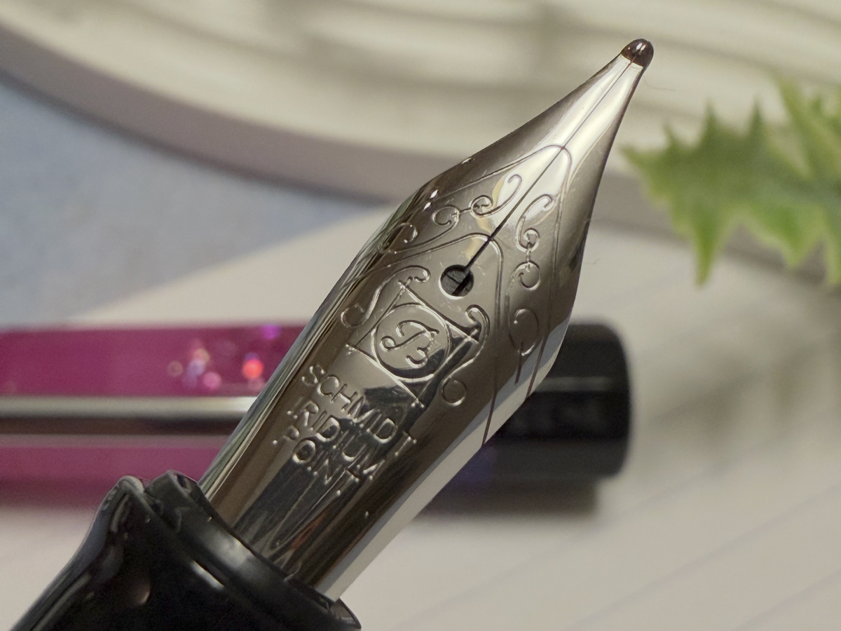 Close-up of a fountain pen nib and upper barrel, showing engraved decorative details on the metal nib.
